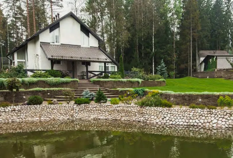 дом с газоном, кустарниками и водоёмом